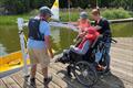 Hoist process step 1 - the sailor has arrived already sitting on the sling (see black fabric hanging over back of wheelchair) and the spreader bar can be attached © Magnus Smith