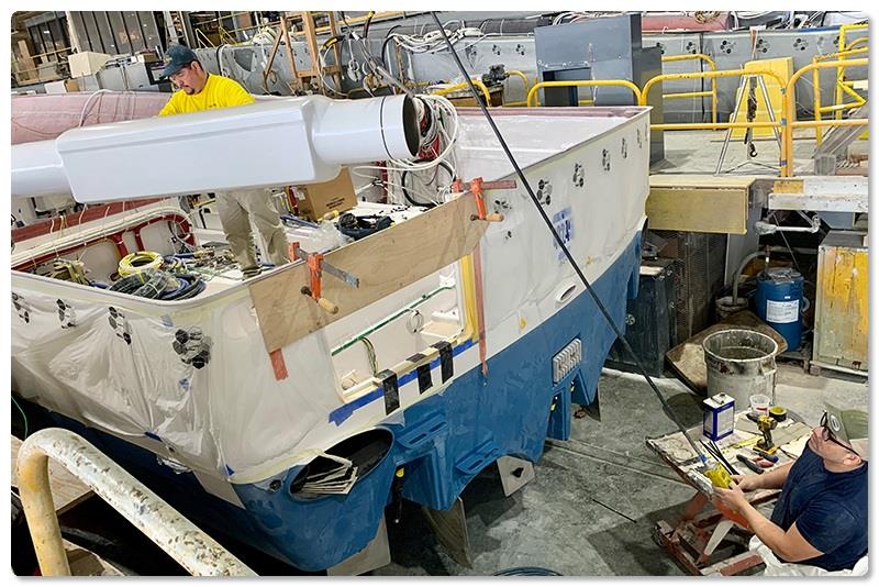 Mechanic Brailler Silva (blue shirt) utilizes an electric overhead hoist to transport the composite component photo copyright Viking Yachts taken at  and featuring the Fishing boat class
