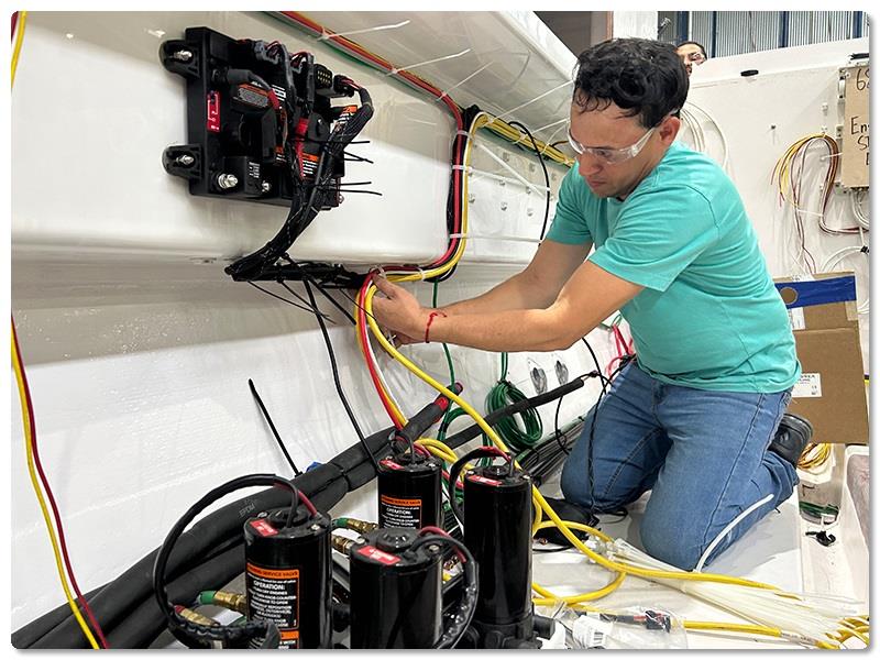 Electrician Jose Zavala runs power cables to the Optimus Electronic Power Steering's pump control module - photo © Viking Yachts
