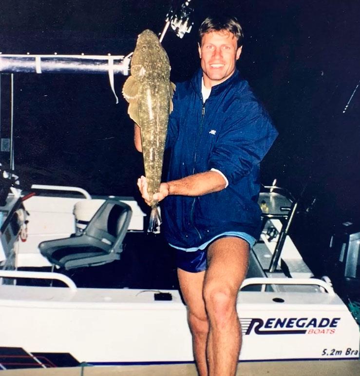 ET as a teenager standing on a wharf with my 5.2m white centre console tied up holding a flathead - photo © Andrew Ettingshausen