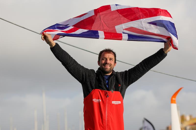 Vulnerable skipper Sam Goodchild (GBR) is photographed with a UK flag after taking 9th place in the Vendée Globe photo copyright Jean-Marie Liot / Alea taken at  and featuring the IMOCA class