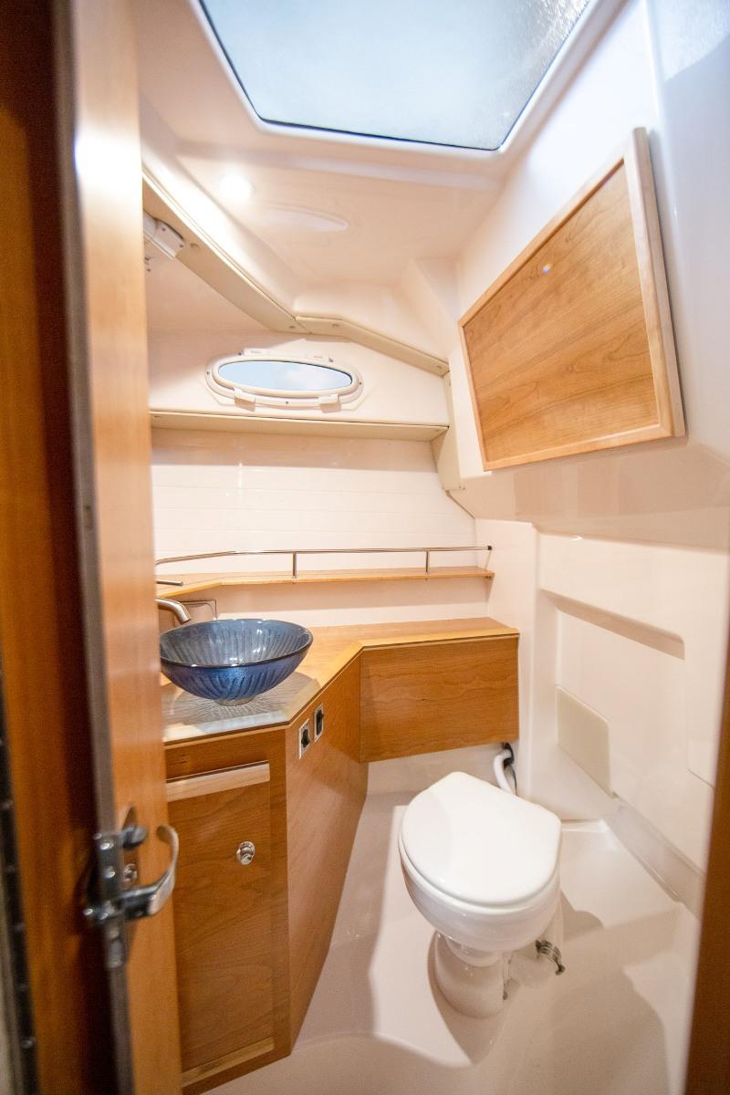 The head is fully appointed with a glass vessel sink, shower wand, electric marine toilet and opening port light. - photo © Cutwater Boats
