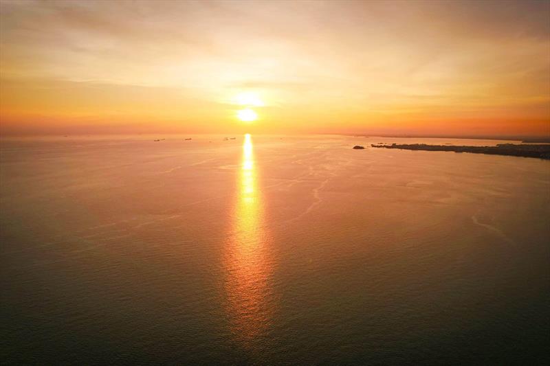 The sun sinks toward the horizon, setting the waters of the Malacca Strait a bright orange photo copyright Riviera Australia taken at  and featuring the Power boat class