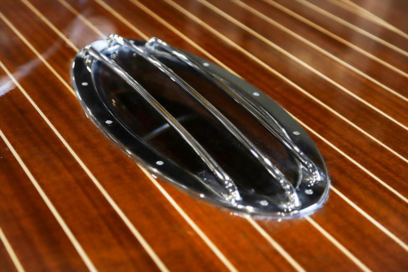 A chrome-rimmed deck window, flush in the mahogany, lighting the cabin below - photo © J Craft Boats